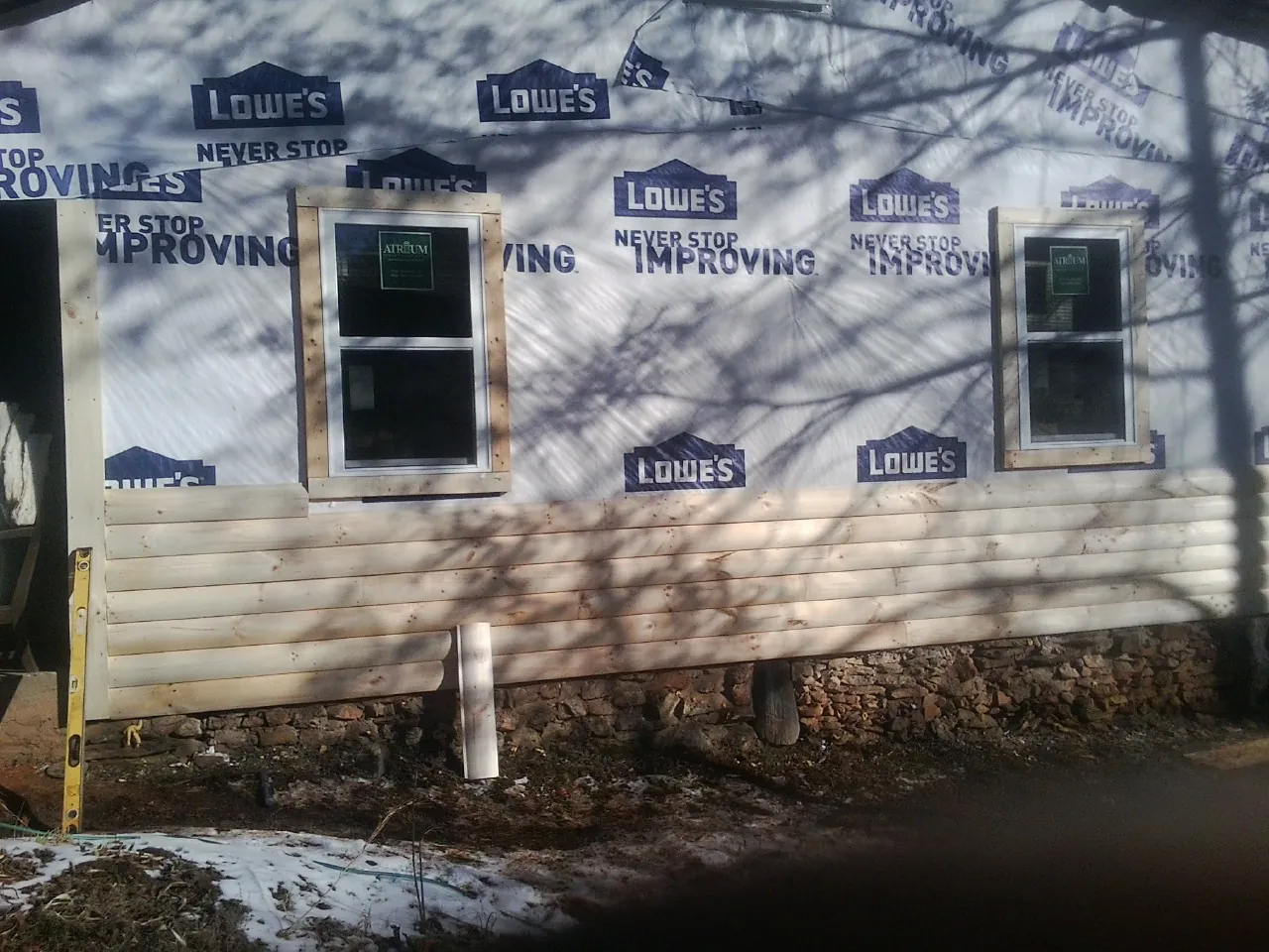House wrap and new log siding going up on an exterior wall in Rockwell