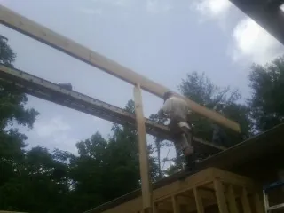 Carpenter setting a ridge beam over a new addition frame — Ice Dam Removal by Roofing Brothers in Rockwell
