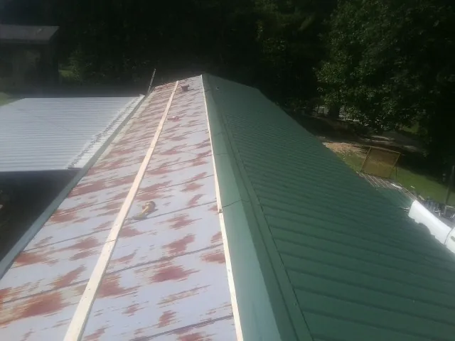Old rusted panels beside newly installed green metal roofing — Wind Damage Roof Repair by Roofing Brothers in Rockwell