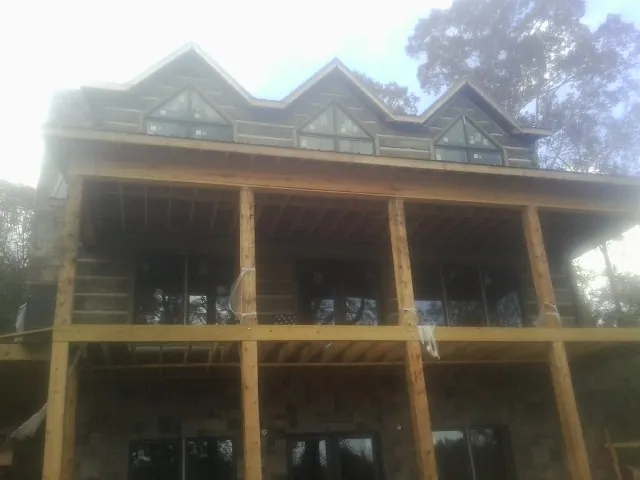 Dormers and porch framing on a large log home under construction — Roof Coating work by our crew in Rockwell