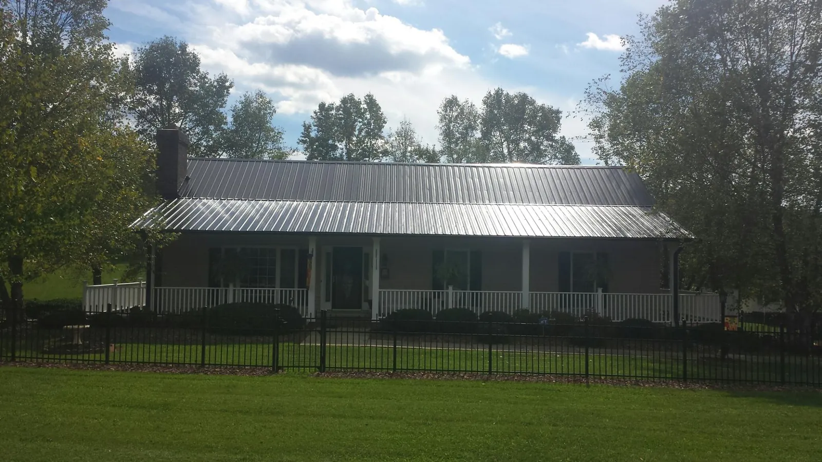 Gray metal roof on a brick ranch with a full width front porch — Gutter Guard Installation work by our crew in Rockwell