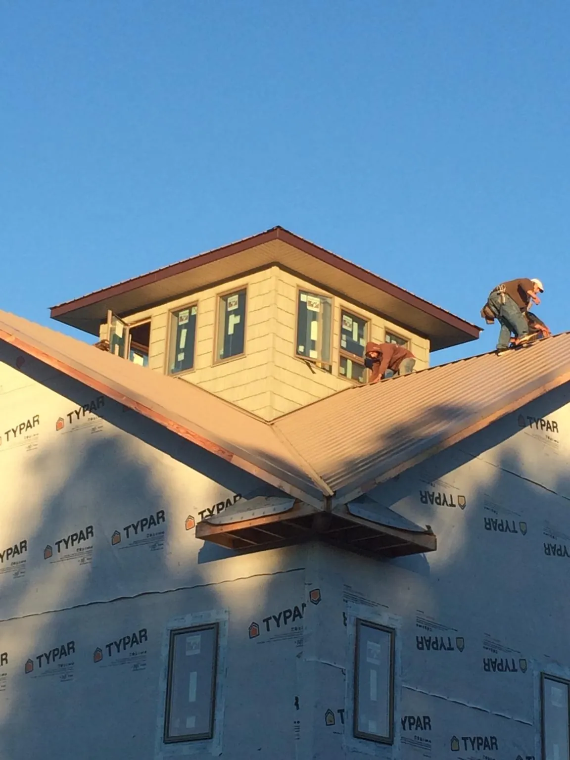 Roofers working around a rooftop cupola on a new metal roof at sunset — Roof Waterproofing in Rockwell by Roofing Brothers
